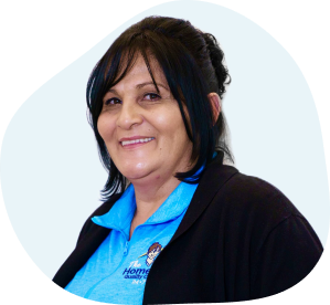close up photo of a caregiver wearing blue work attire and smiling